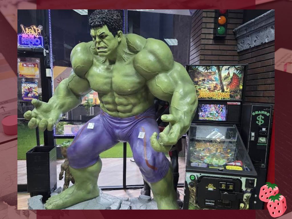 A life sized statue of The Hulk is pictured next to a Jurassic Park pin ball machine.