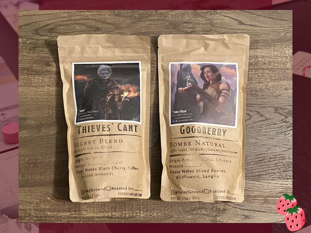 Two bags of coffee beans, one named Thieves' Can't and one named Goodberry are shown on top of a wooden surface. Both include a fantasy drawing.