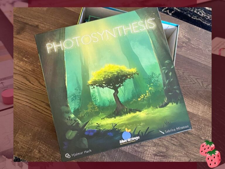 Photosynthesis strategy board game box featuring colorful layered trees and forest artwork, photographed on a wooden table before gameplay.