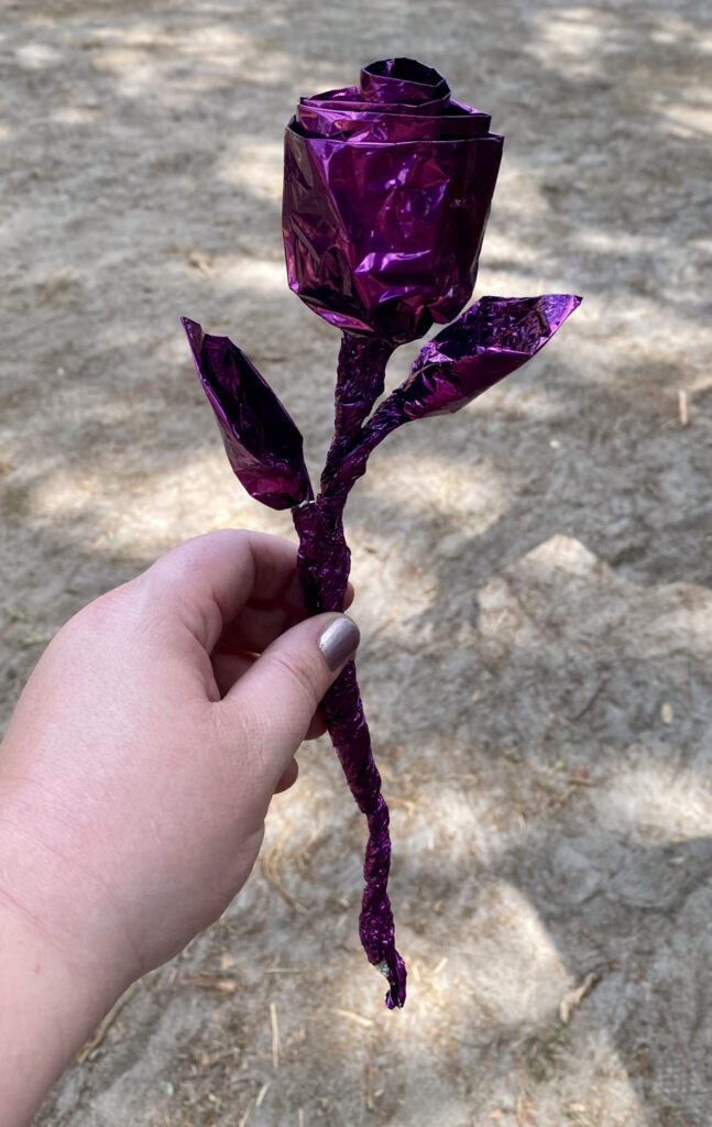 Variant berry holds a handcrafted foil rose made by an artisan at the Bay Area Renn Festival