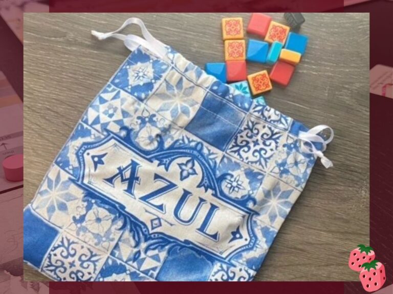 Cloth draw bag with a blue and white tile pattern and the Azul logo is in the center of the frame. Colorful, resin tiles spill out of the top.