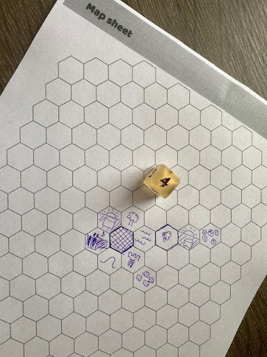 Hand-drawn game map on hex grid paper for the solo game Bumbling, featuring a rolled die and sketched terrain icons representing explored areas and obstacles.