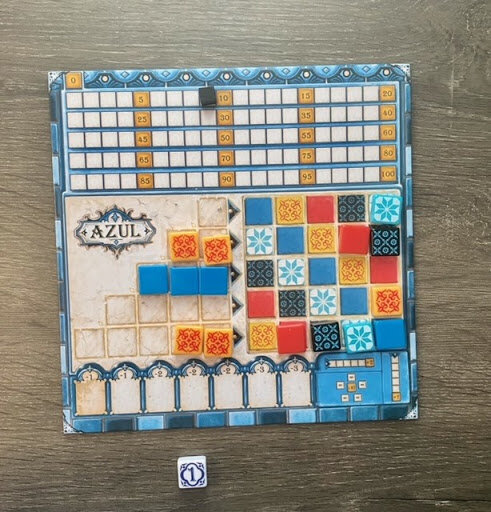 Azul player board with scoring track, wall pattern, and partially completed tile rows, showing an in-progress game setup on a wooden tabletop.