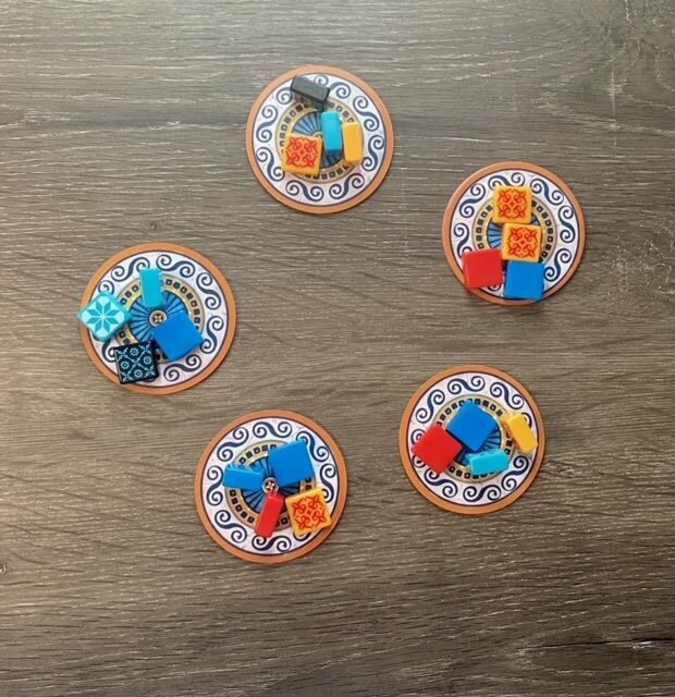 Circular factory display discs filled with assorted Azul tiles, arranged on a wooden table during gameplay.