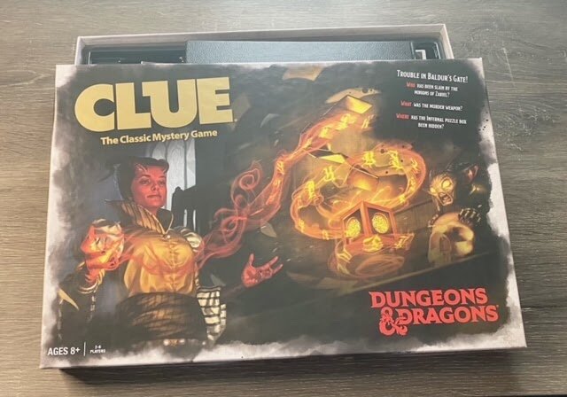 Clue: Dungeons & Dragons edition game box featuring fantasy artwork of characters, glowing magic, and a dragon-themed mystery setting.