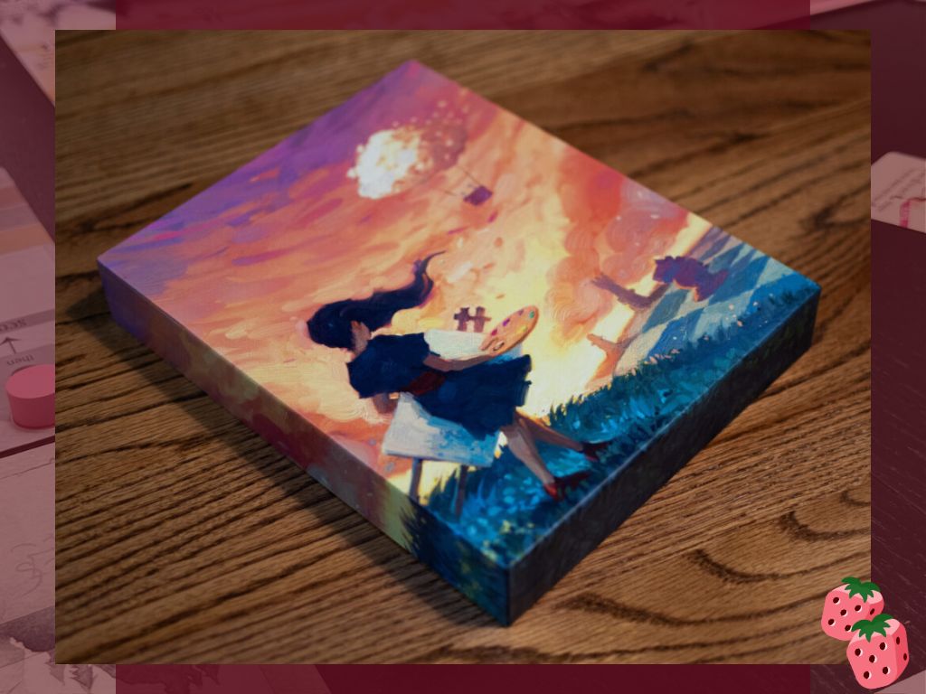 The box for the game Canvas is pictured on a wooden surface. The art on the box features a female figure in a dress, looking away from the camera, carrying an easel, canvas and pallet of paint.