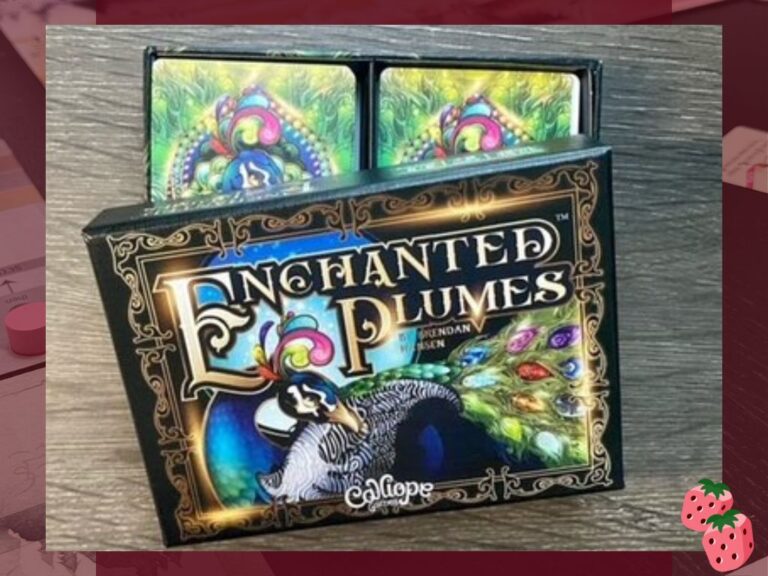 A box reads Enchanted Plumes on the top center, picturing a peacock in the center. Box top is partially opened, revealing 2 decks or cards inside.