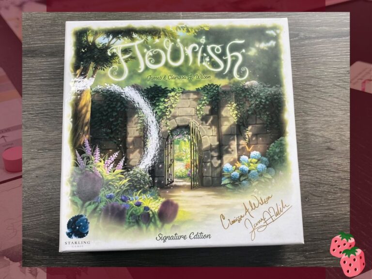 The board game box for Flourish is pictured on a wooden surface. It shows a garden scene with an open door in a rock wall.