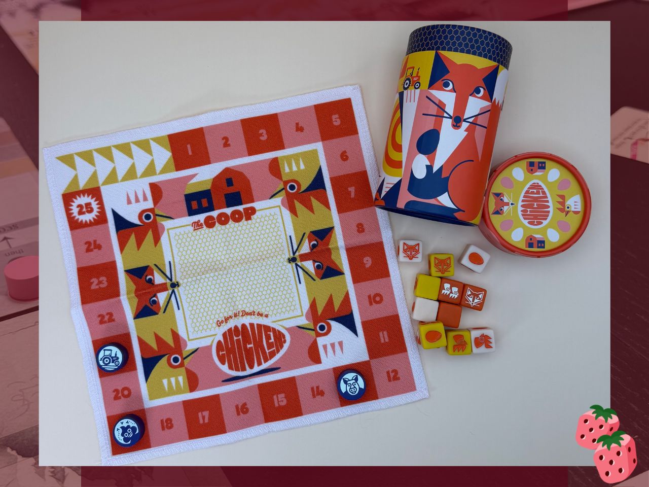 Game spread for Chicken! the game. It shows a cloth game board, several playing dice with different symbols, and the cylinder game box with the lid removed.