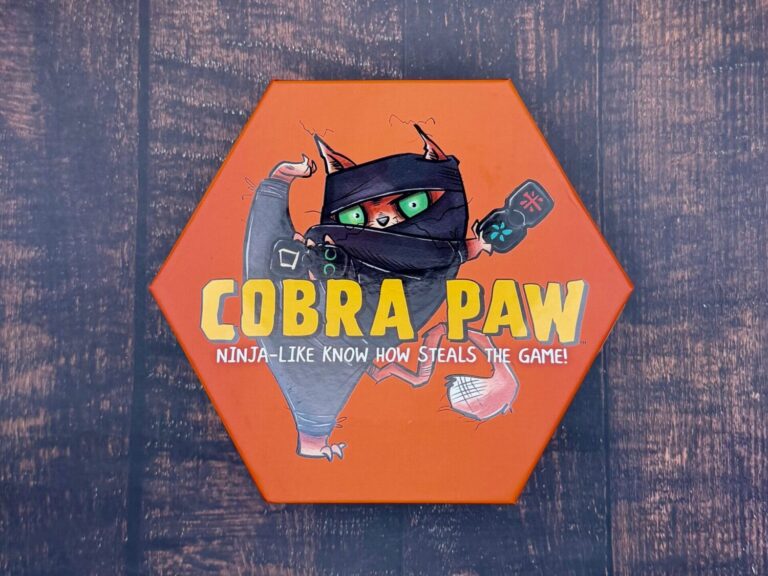 An orange, hexagon top reads Cobra Paw - Ninja like know how steals the game on top of a wooden surface.