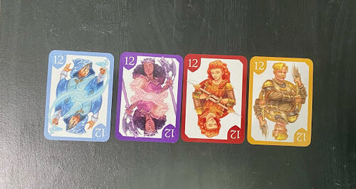 4 cards showing the number 12 are lined up in a row. Card depict different fantasy humanoid. Card colors are blue, purple, red and yellow.