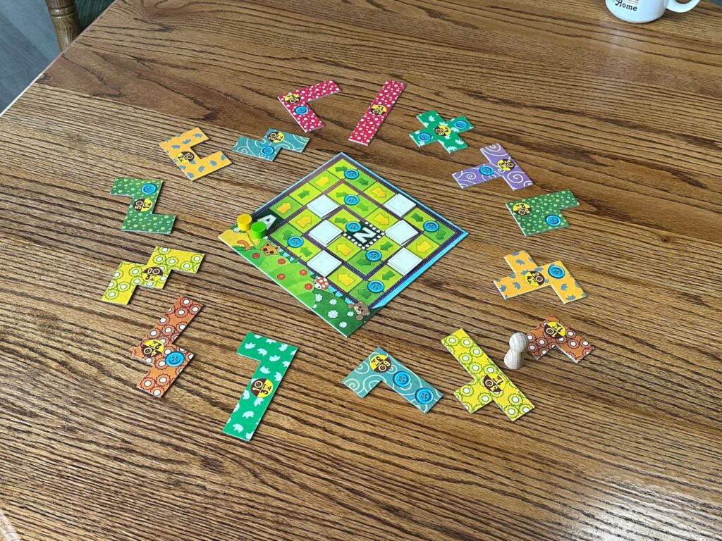 The patchwork game board is in the middle of a wooden table with various shaped patchwork pieces around it. A yellow and green meeple are at the starting square. 
