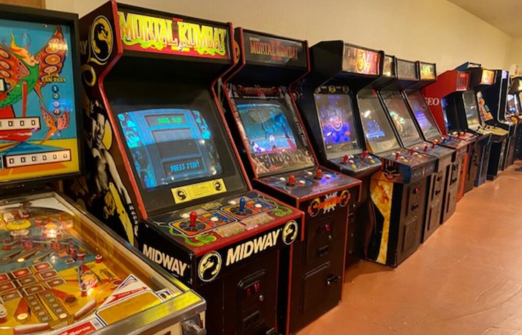 A series of retro arcade style games are lined up against a wall.