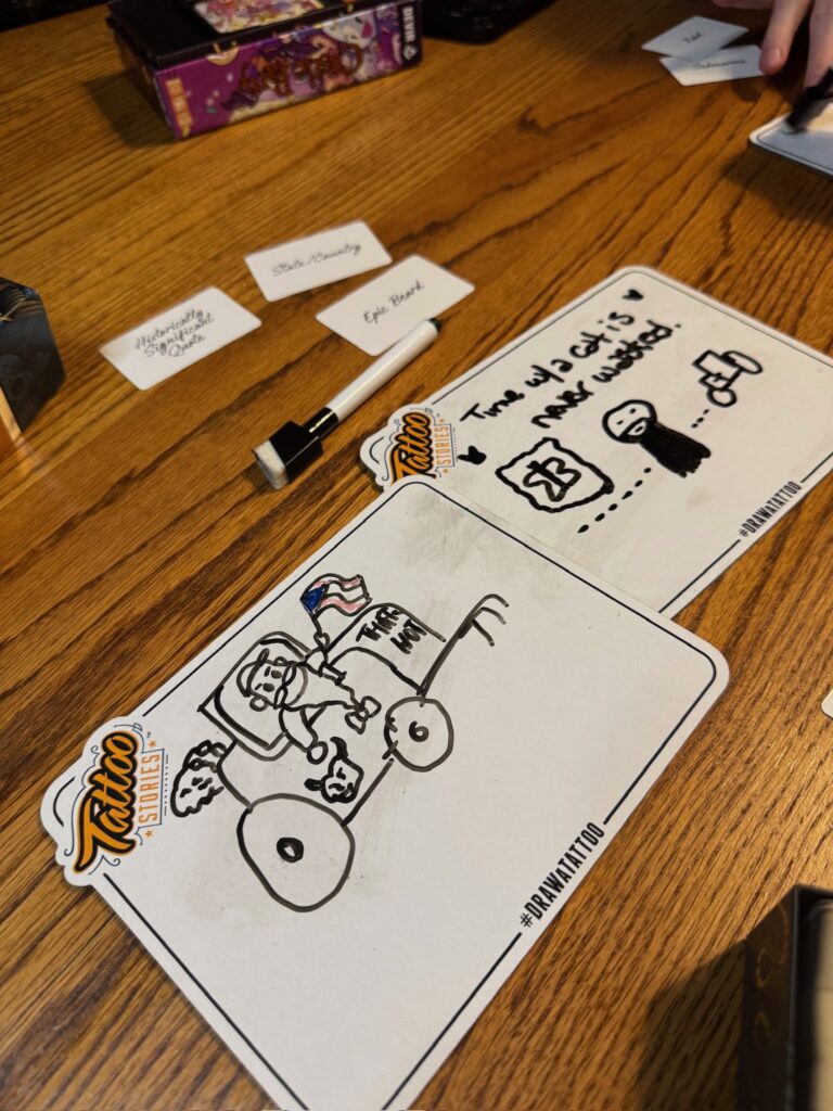 Two small white boards are pictured with hand drawn images on the. In one picture is a man in a tractor and the other has a person standing in front of a tractor. a marker is in the bop of the picture along with some obscured prompt cards.
