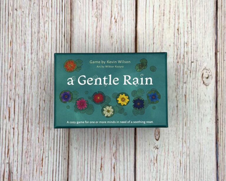 A small blue box sits on a wooden surface. The box is titled A Gentle Rain.