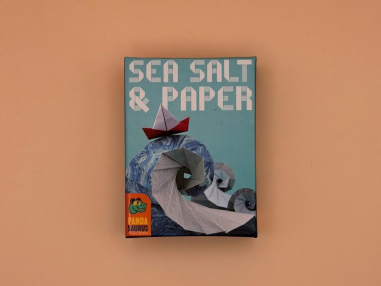 Pictured is the game box for Sea Salt and Paper with the Pandasaurus logo on it. On the box is an origami sailboard on top of origami waves.