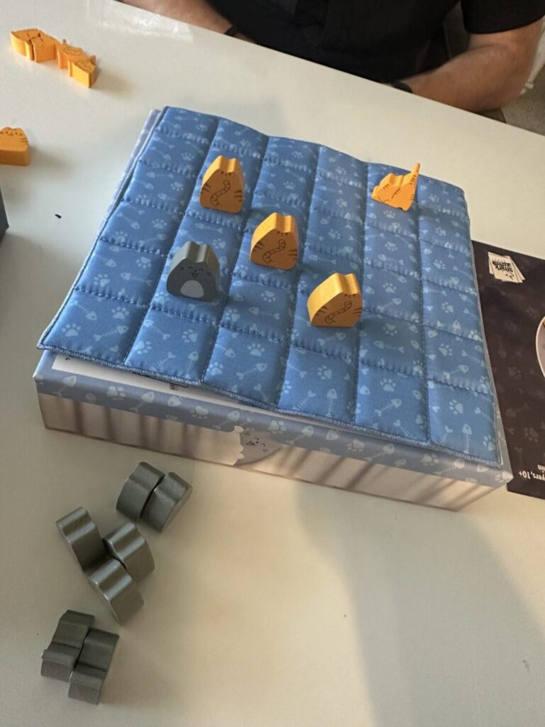 The image depicts the boop bed with quilt on top and three orange cats in a diagonal row.