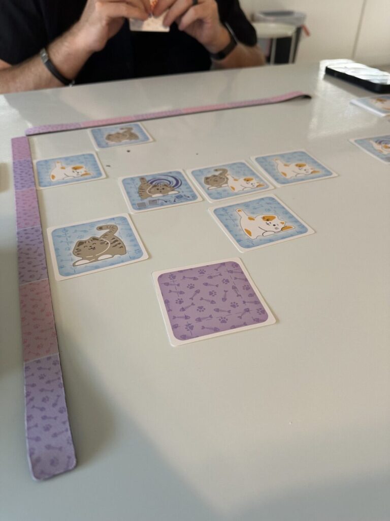 boop shuffle game play set up. Two edge rulers are in an L shape and cat and kitten cards are inside of the grid.