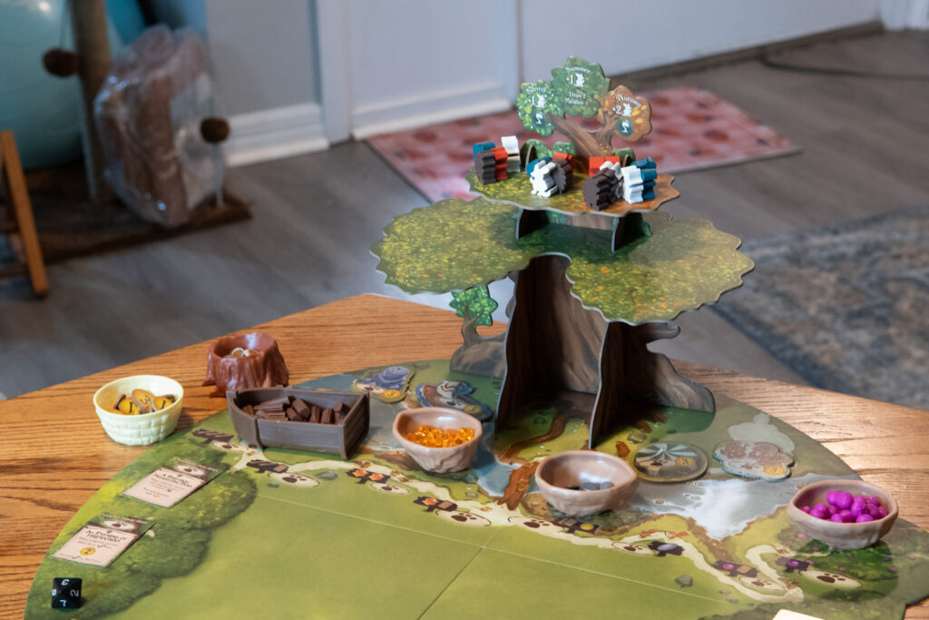 Close up of the Ever Tree on the Everdell game board. Critter meeples are on the top level of the tree. Resources for the game are at the bottom of the tree.