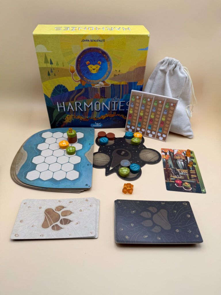 The board game box for Harmonies is featured in the background and all game components are pictured.