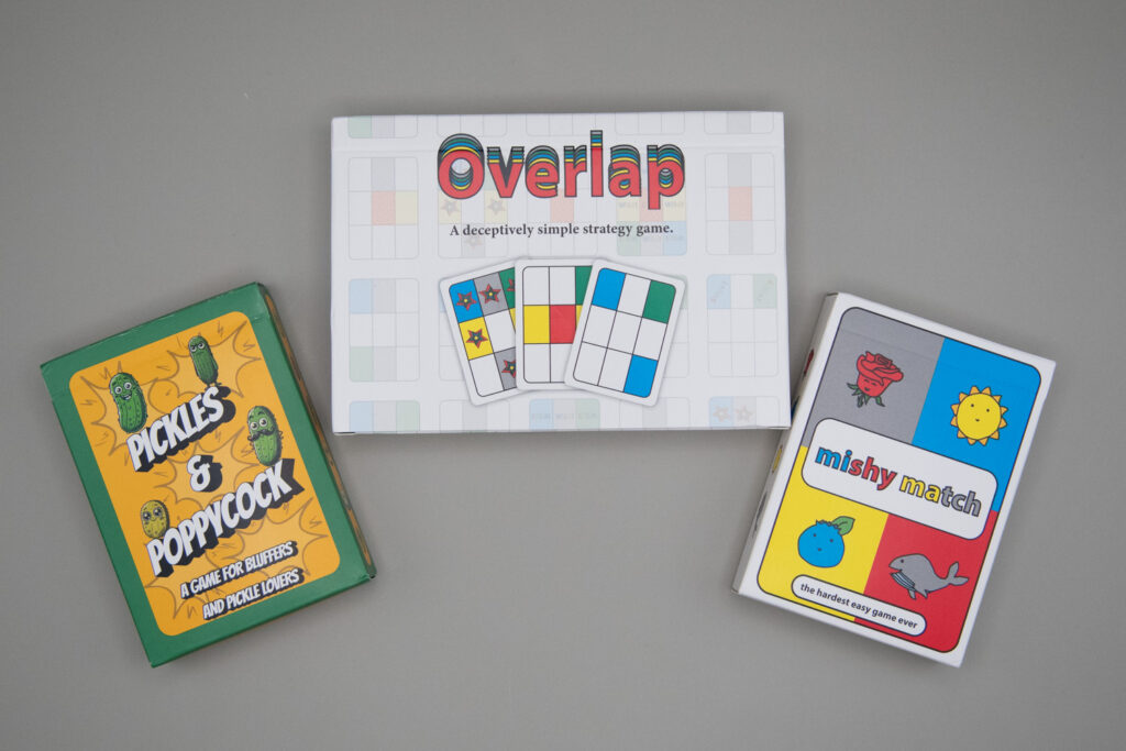 Three card boxes read, front left to right, Pickles & Poppycock, Overlap and mishy match.