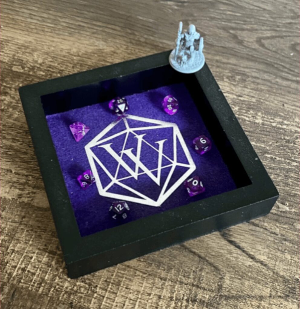 A black and purple dice tray with 7 polyhedral does inside of it. On the corner stands a mini figure of a short female presenting humanoid